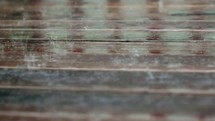 Looped video of rain falling on plank wood.