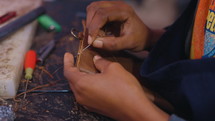 Woman pushes a needle and thread through a leather wallet