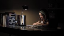 young girl sitting at a desk reading a Bible 