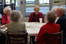 Seniors at a round table playing dominoes.