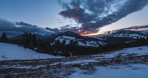 Time lapse of fast clouds sky over winter alps mountains landscape after sunset in cold blue evening