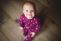 a smiling infant in heart pattern pajamas 