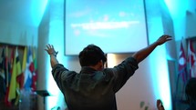 young man with hands raised high during a worship service 