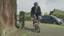 Businessman cycling to work on childs bike 