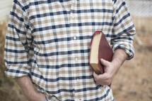 a man in a plaid shirt holding a Bible 
