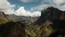 Scenic aerial drone view of a green valley in Madeira with small towns surrounded by majestic mountains, Portugal