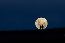 silhouettes in front of a full moon 