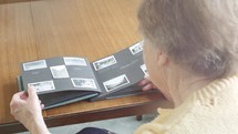 elderly woman looking at an old photo album 
