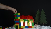 a person building a church out of colored wooden blocks 