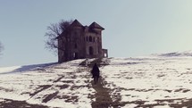 person in a cape walking towards a castle 