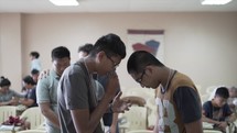 men and boys praying in a classroom 