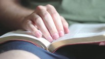 Man's hands turning pages of the Bible.