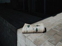 A rolled up newspaper laying in the sun.