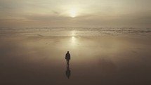 a man walking on a beach at sunset 