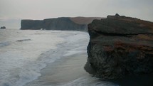 tide washing onto a beach and sea cliffs 