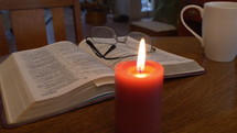 Dolly shot of Bible, candle, and coffee for morning devotions