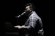 man singing into a microphone and playing a piano 