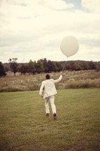 man in a suit running holding a white balloon