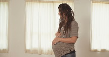 Pregnant woman holding and rubbing her belly.
