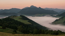 Sunbeams moving over foggy mountain valley at sunrise. Mist morning in beautiful rural landscape time lapse
