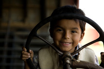 Young boy holding a steering wheel