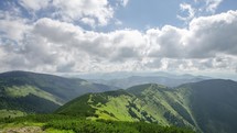 Beautiful white clouds in sky flying over green landscape in mountains time lapse
