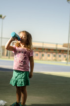 A young girl drinking from a water bottle.