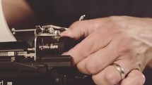 Hands inserting paper in a vintage typewriter.