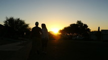 Silhouette of a couple walking in a neighborhood at sunrise