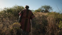 Follow shot of a Bible prophet walking up a desert hill