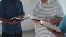 men reading Bibles and discussing scripture 