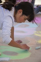 a child coloring with sidewalk chalk 
