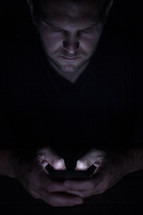 a man texting in darkness