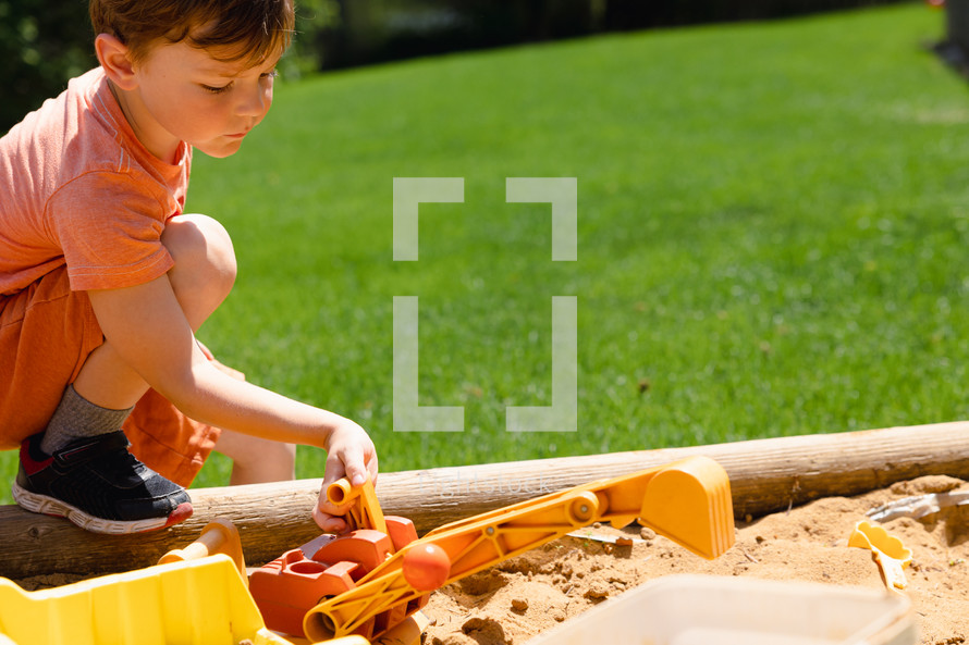 a boy playing in a sandbox 