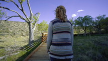 a young woman walking on a wooden path 