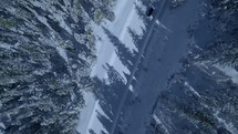 aerial view over a winter forest and car on a snow covered road 