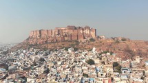 Aerial footage of a large palace on top of a hill above the vast city of Jodhpur, India. 