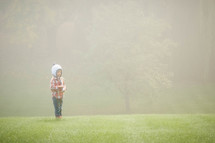 a girl standing outdoors in the fog 
