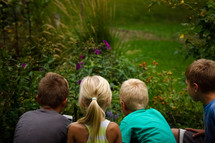 kids watching creatures in a flower garden 