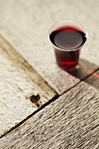 A communion cup filled with wine sits on a wooden table