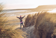 a girl child standing on a beach in a winter coat 