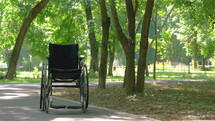 Wheelchair left empty outdoors in park in summer. 
