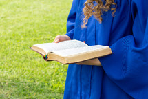 portrait of a female graduate outdoors holding a Bible 