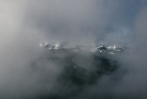fog and clouds over snow capped mountaintops 