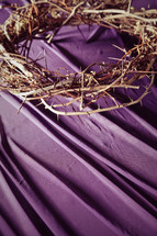 Crown of thorns on purple drape.