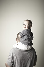 A young son sits on his father's shoulders