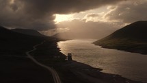 Aerial view of an empty highway in Scotland UK during sunset with river, mountains and dramatic clouds