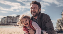 Father and child on the beach smiling 