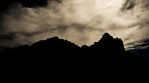 Clouds behind silhouette of rock formations.