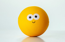 Yellow ball with a happy expression on a white background representing happiness and joy